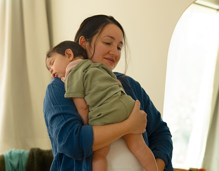 happy mom with sleeping baby on shoulder